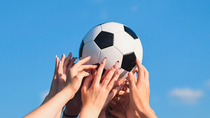 School friends holding soccer ball together under blue sky, showing teamwork and sportsmanship