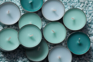 A collection of tealight candles in soft pastel shades of blue and green arranged closely together...