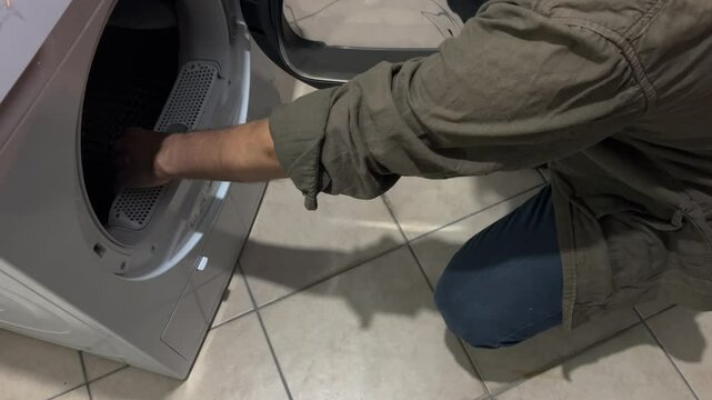 The man is cleaning the dryer filter.