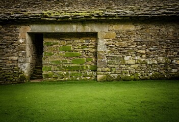 A stone building with moss growing on the walls.