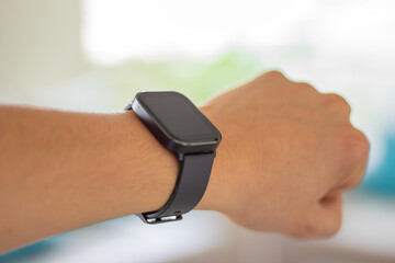 Close-up of a wrist wearing a black smartwatch with a blank screen. Concept of wearable technology,...