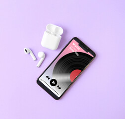 Mobile phone with open music player app, earphones and case on light violet background, top view