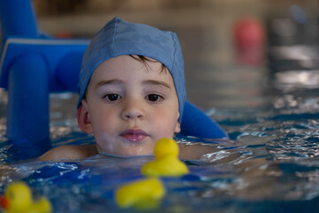Child playing with rubber ducks in swimming pool