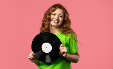 Pretty woman dancing with vinyl record disc on pink. Hobby, music, collection