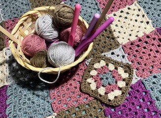 Crochet granny square, clews and hook on crochet blanket background photo
