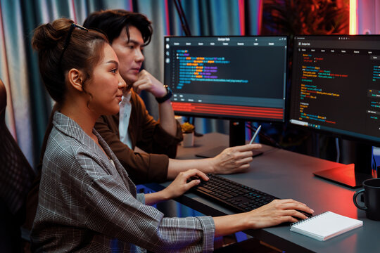 IT developers discussing with point to intelligent website development coder system running data online two screens information technology at neon light room at modern office. Infobahn.