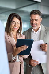 Busy professional corporate business executives man and woman in suits holding tablet tech device...