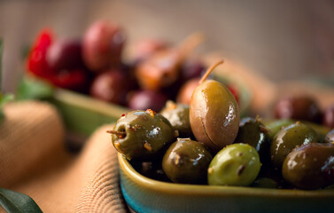 Olives, homemade marinated colorful olives with herbs and spices on rustic table, close up. Healthy Mediterranean vegan food 