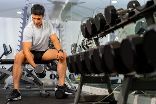 Healthy Asian man athlete do sport training workout exercise weight lifting dumbbell at fitness gym. Sportsman bodybuilding with weight training equipment. Wellness healthcare motivation concept.