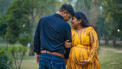 Happy pregnant couple in outdoor park, Husband with his pregnant wife in nature, married indian couple expecting baby concept