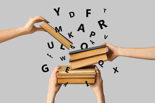 Hands holding many books on grey background