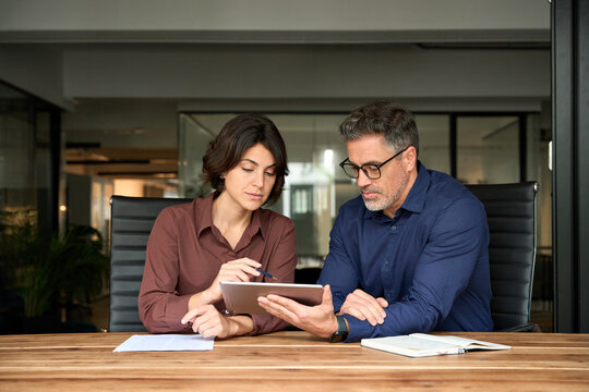 Business team people having discussion planning sales financial strategy in company using tablet working together in office. Two busy business colleagues having conversation at corporate meeting