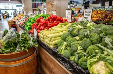 Displays of various fresh vegetables for sale at an Australian grocery market inside a shopping center, complete with prices for customers to choose from.