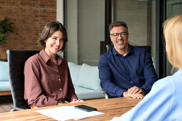 Friendly recruitment hr manager interviewing young woman, holding cv listening to candidate at corporate group meeting or job interview. Happy business people team working together in office boardroom