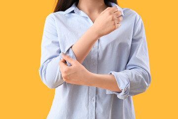 Young woman rolling up her sleeve on  yellow background