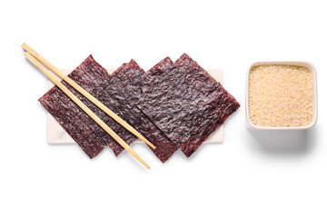 Board with natural nori sheets, chopsticks and bowl of rice isolated on white background