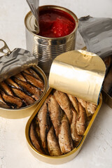 Opened tin cans with sprats in oil on light table