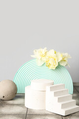 Decorative plaster podiums with daffodils on tile against grey wall