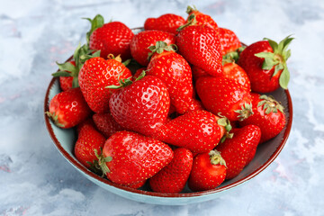 Bowl with fresh strawberries on blue background