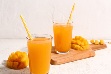 Glasses of fresh mango smoothie on light background