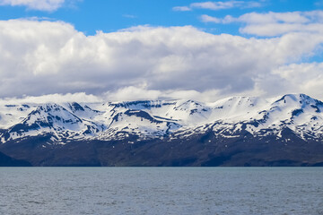 Snowy mountains reflecting in the Iceland sea under cloudy sky