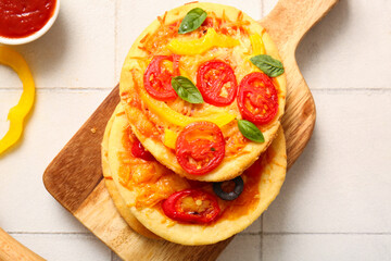 Board with different tasty mini pizzas on white tile background