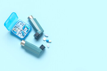 Asthma inhalers and box with pills on blue background