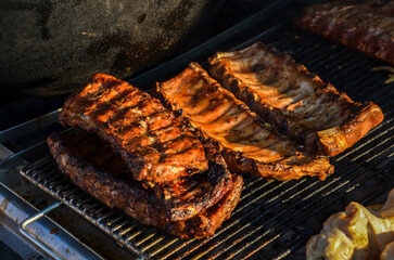 Succulent barbecue pork ribs sizzling on a grill, emphasizing outdoor cooking and barbecue joy. Capturing the essence of summer grilling with perfectly cooked meats over an open flame
