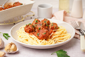 Plate of boiled pasta with tomato sauce and meat balls on white table