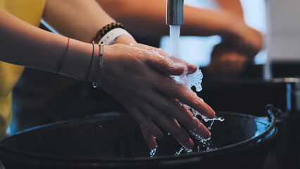 Woman carefully washing her hands with soap and water in a basin, promoting hygiene and cleanliness