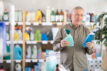 Senior man buyer select and studies label, read composition of kitchen cleaner spray. Client examine product, make purchase decision and discusses advantages and properties of product.