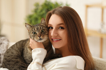 Pretty young woman with cute tabby cat at home, closeup