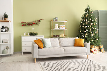Stylish interior of modern living room with comfortable sofa and Christmas tree
