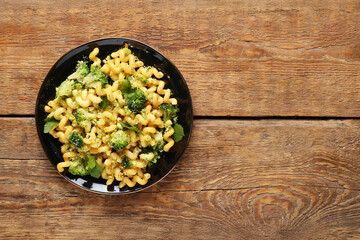 Plate of tasty pasta with broccoli on wooden background