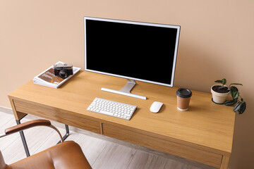 Stylish workplace with modern computer and cup of coffee near color wall