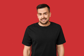 Handsome ashamed young man on red background