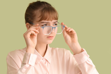 Young businesswoman in eyeglasses squinting on green background, closeup. Glaucoma awareness month