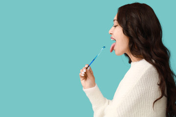 Young Asian woman with tongue scraper on blue background