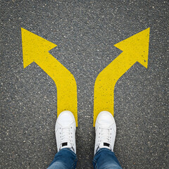 Feet stand at a crossroads with two yellow arrows pointing in opposite directions on asphalt. Generative AI.