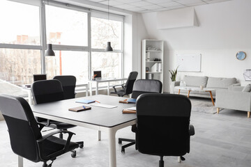 Table, armchairs, board and stationery prepared for business meeting in stylish conference hall