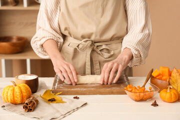 Woman preparing tasty pumpkin strudel on table in kitchen