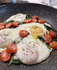 Indulge in Delicious Poached Eggs served with Fresh Spinach and Vibrant Cherry Tomatoes