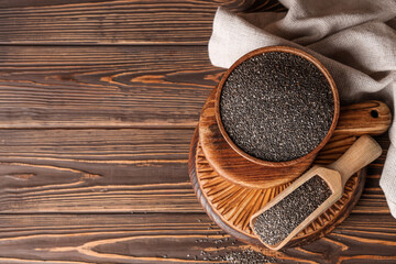 Bowl and scoop with chia seeds on wooden background
