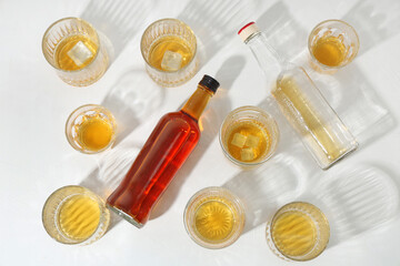 Bottles and glasses of cold rum on white background