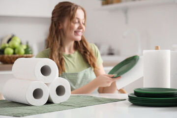 Young woman with paper napkin wiping dish in kitchen
