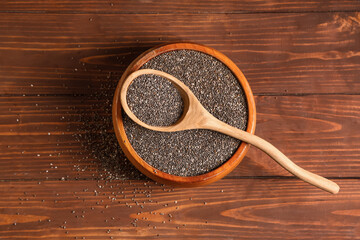 Bowl and spoon with chia seeds on wooden background