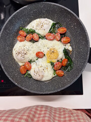 Enjoy delicious poached eggs with fresh spinach and cherry tomatoes, beautifully cooked
