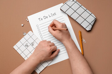 Male hands with to-do list, notebook and pencil case on brown background
