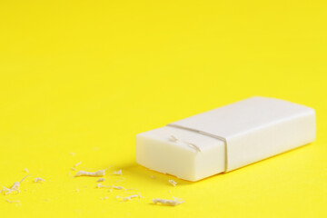 One eraser and scraps on yellow background, closeup. Space for text