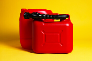 Two red plastic canisters on yellow background